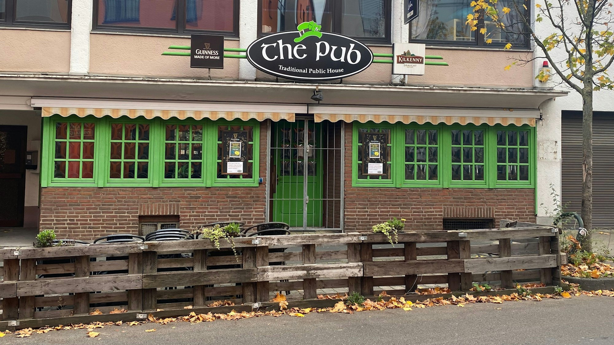 Blick auf die Fassade des The Pub. Die Fensterläden und die Eingangstür sind knallgrün gestrichen.