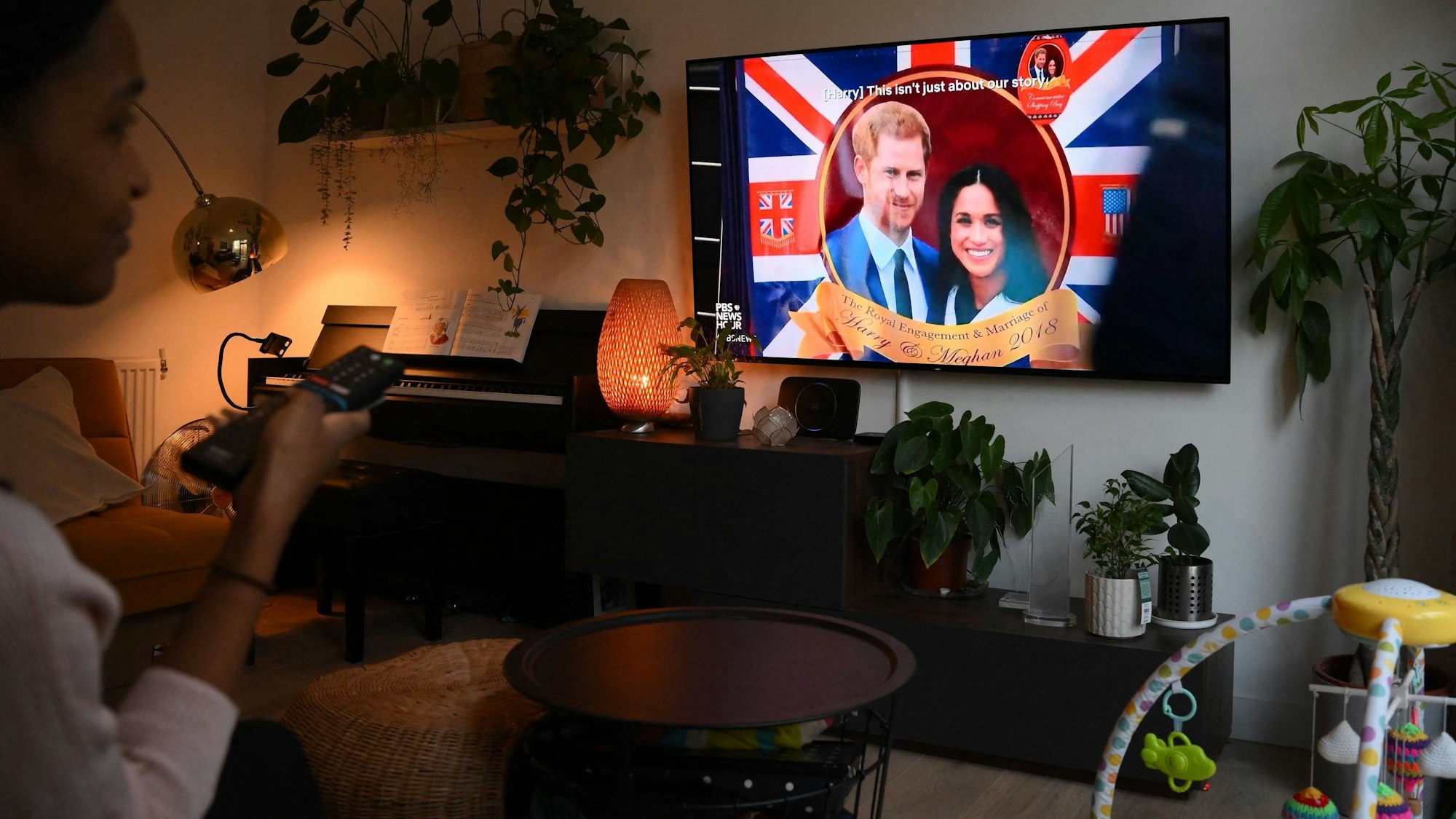 Eine Frau schaut auf einem Fernseher, auf dem die Netflix-Doku „Harry and Meghan“ läuft.