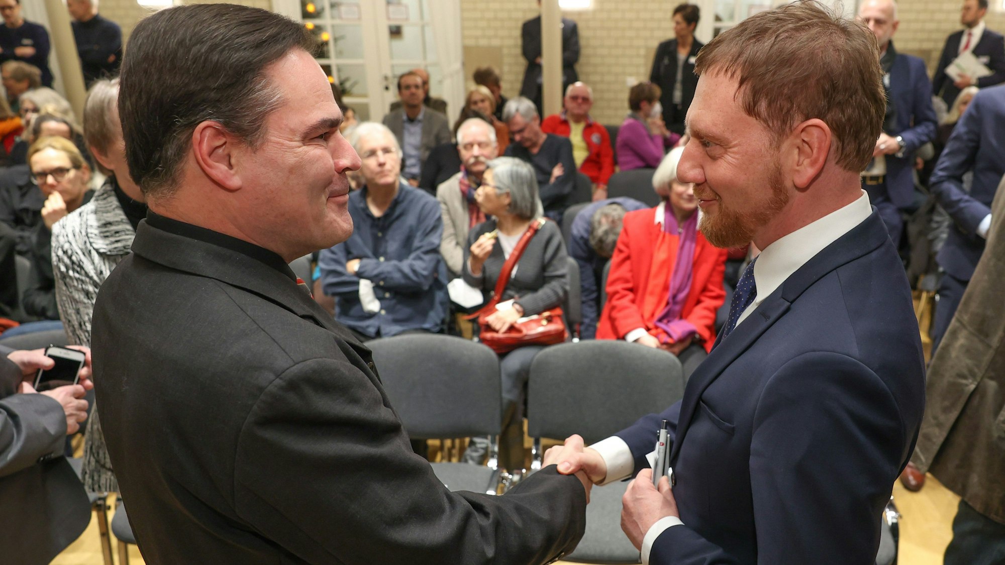 Der Autor Uwe Tellkamp (l) und Sachsens Ministerpräsident Michael Kretschmer (CDU) begrüßen sich bei einer Lesung in der Landesvertretung Sachsens.