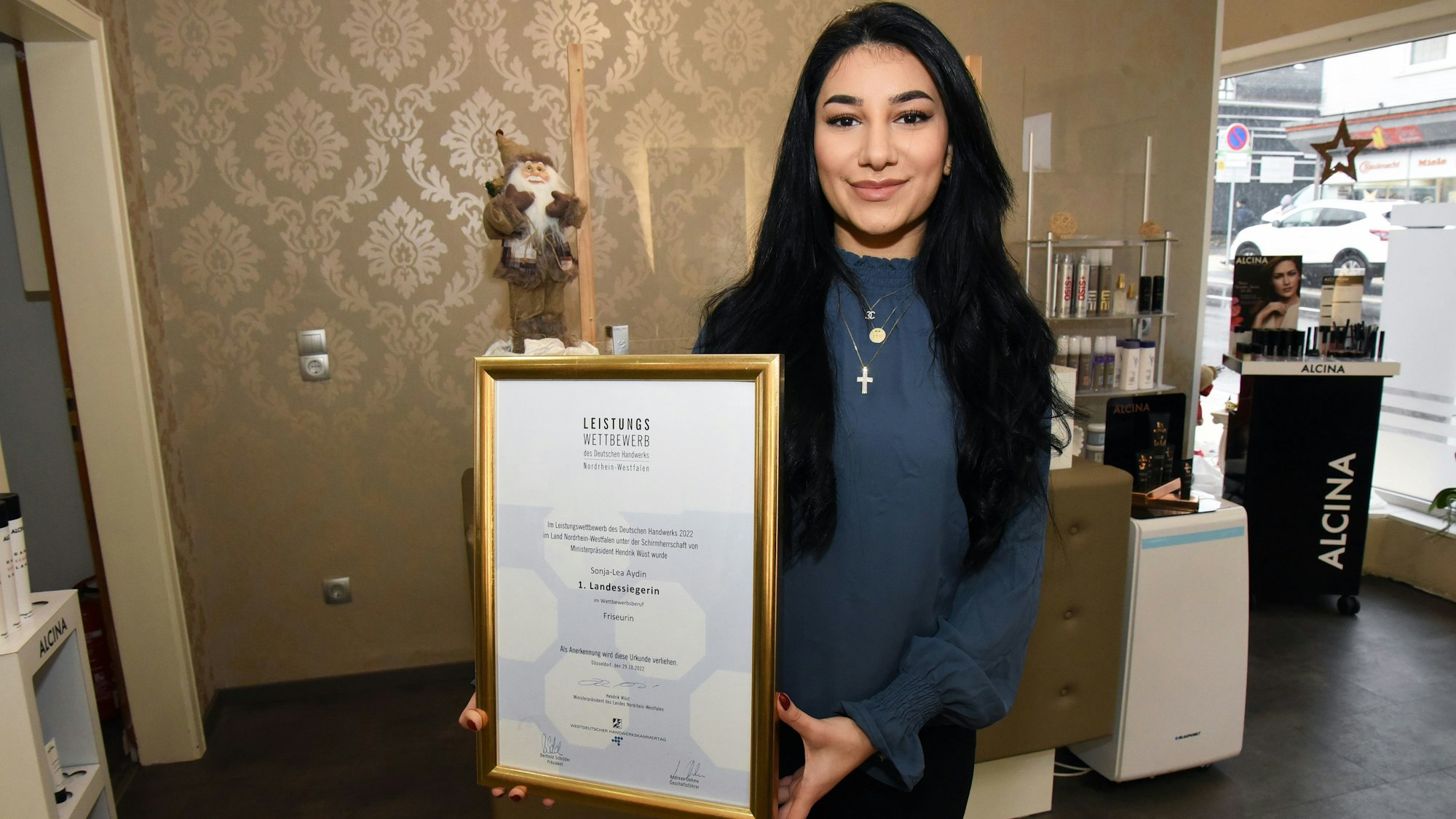 Die Marienheider Friseurin Sonja Lea Aydin hält stolz ihre Urkunde als Landessiegerin im Leistungswettbewerb des Deutschen Handwerks in die Kamera.