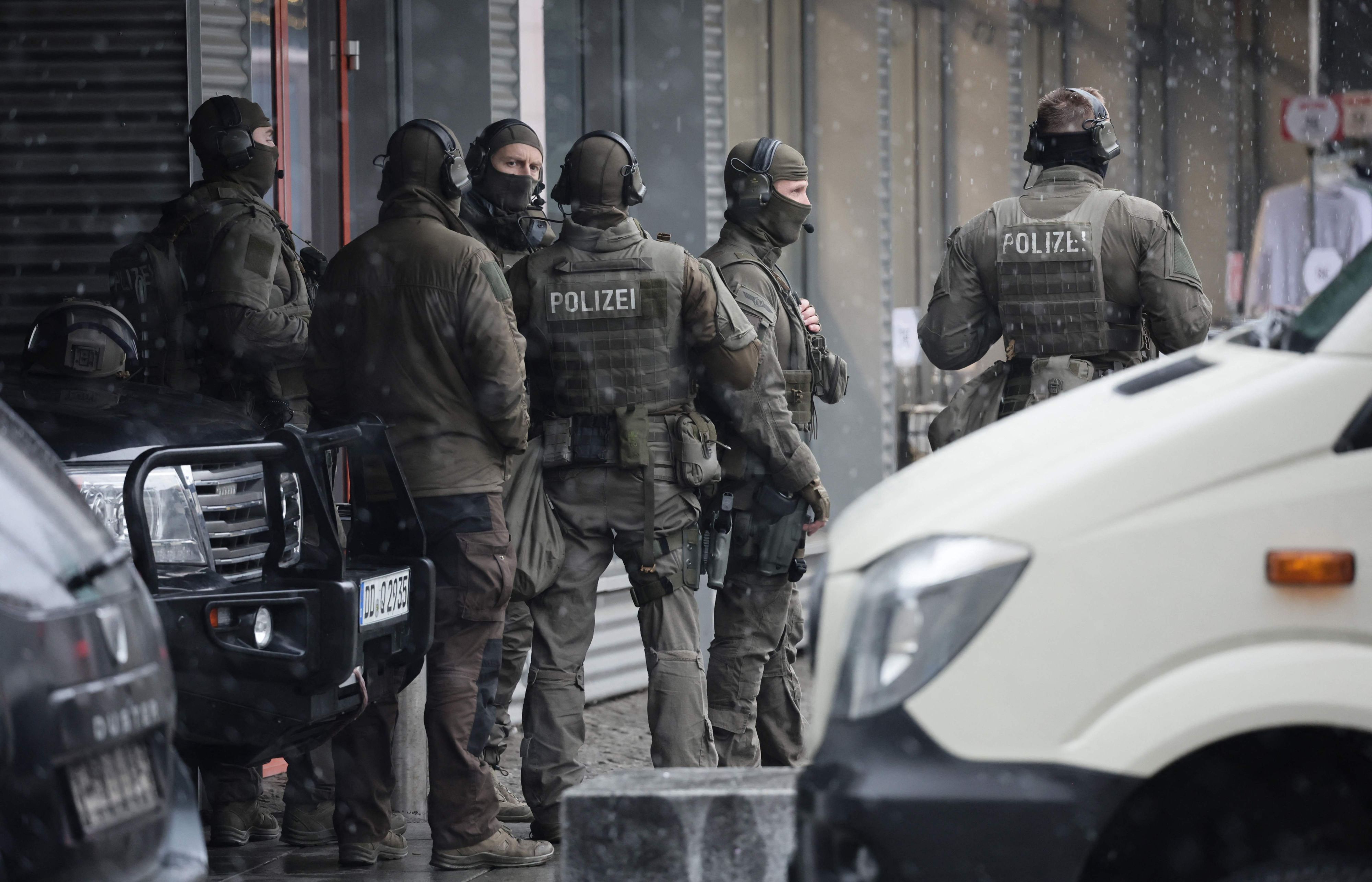 Sechs Männer in Uniformen des SEK stehen auf einer Straße zwischen Autos.