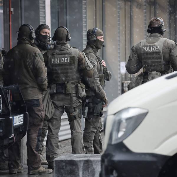 Sechs Männer in Uniformen des SEK stehen auf einer Straße zwischen Autos.