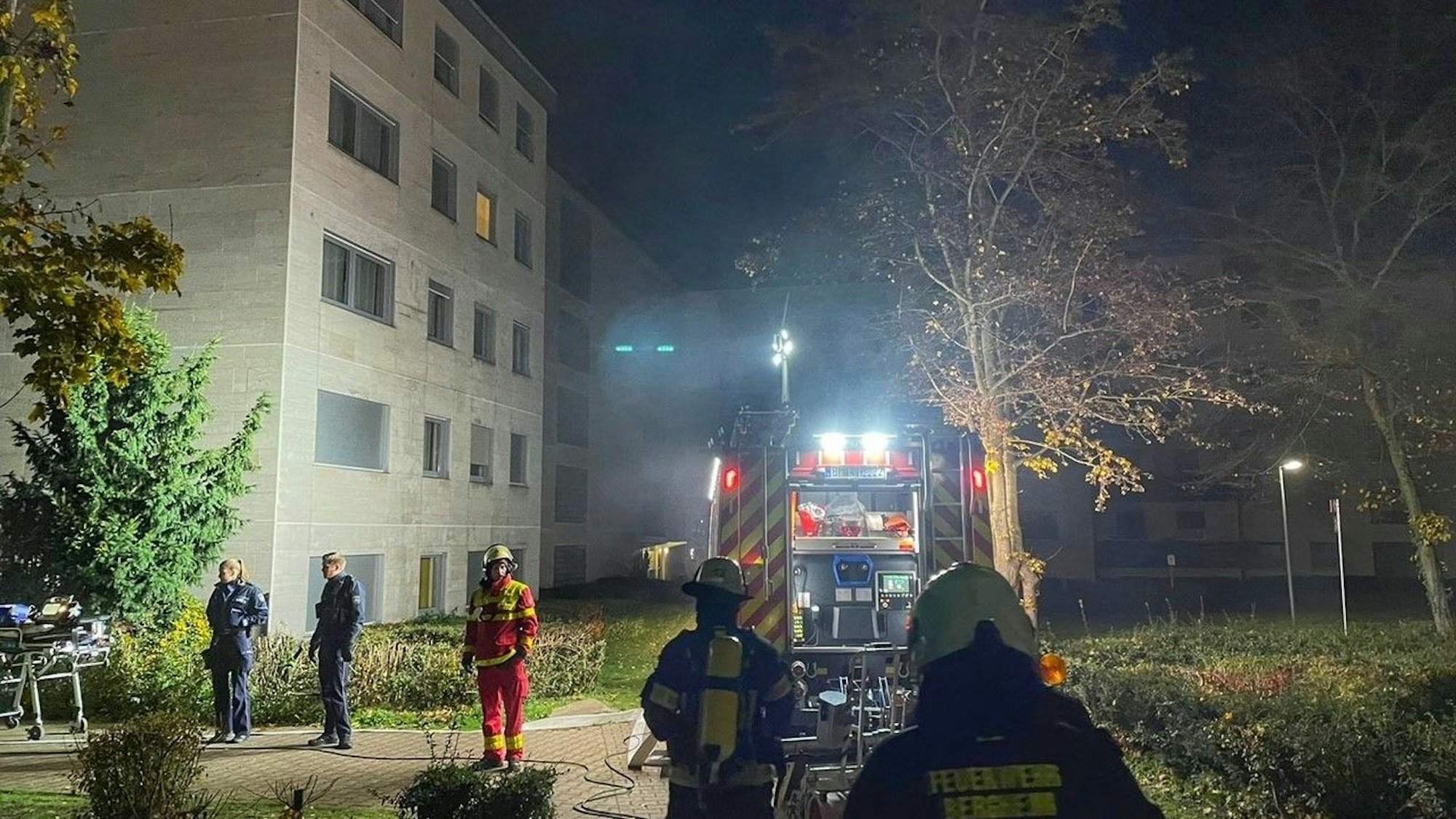 Das Bild zeigt Einsatzkräfte der Feuerwehr Bergheim vor einem Mehrfamilienhaus.
