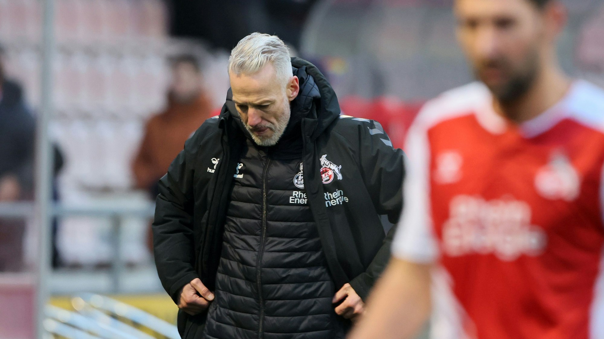 Ein Fußballtrainer verlässt mit enttäuschter Miene den Platz.