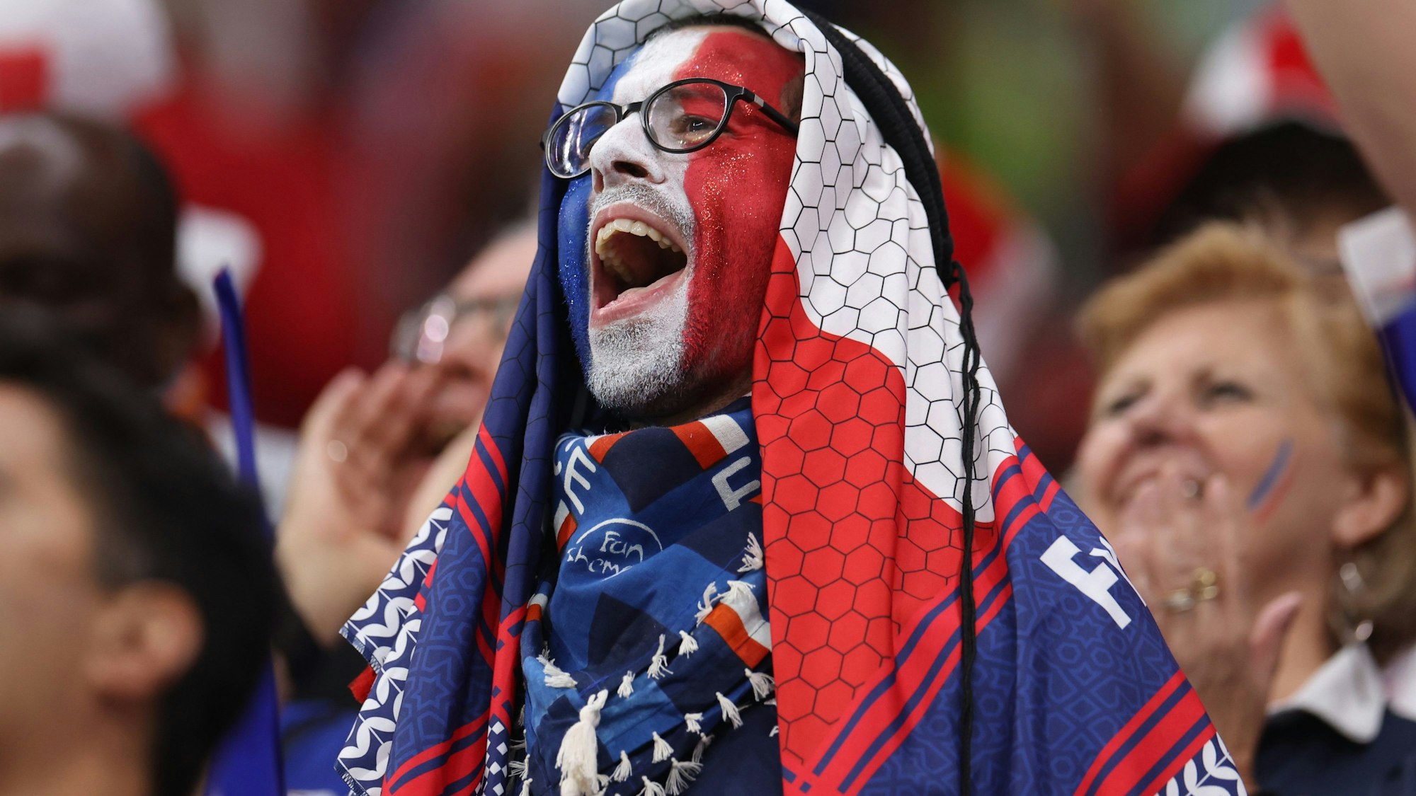 Ein französischer Fan hat sein Gesicht in den Landesfarben Blau-Weiß-Rot angemalt und feuert seine Nationalelf in Katar an.