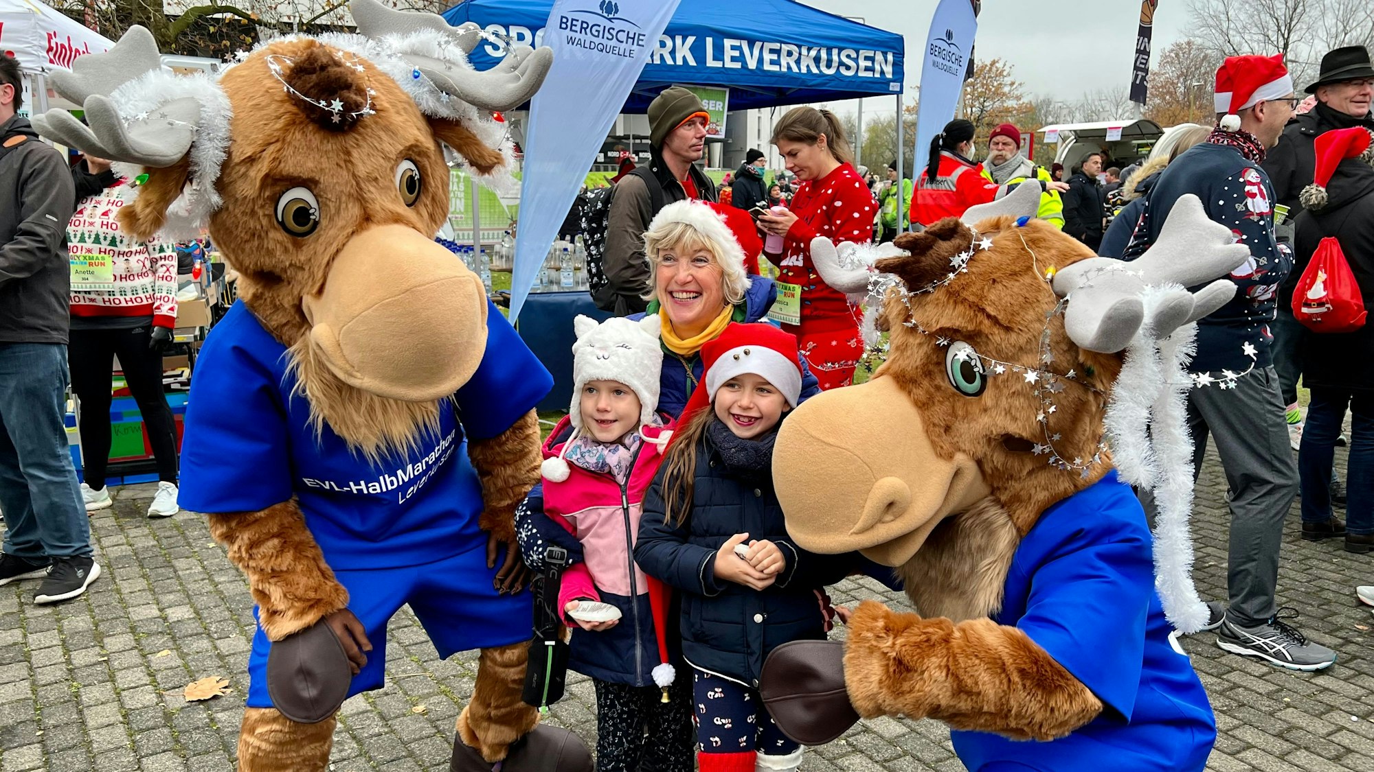 Als Elche verkleidete Mitarbeitende des Stadtparks Leverkusen posieren mit Kindern und Teilnehmern zum Start des Ugly Sweater Run an der Ostermann-Arena