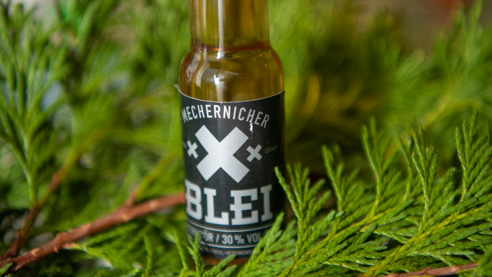 Ein Fläschchen Mechernicher Blei steht auf Tannenzweigen.