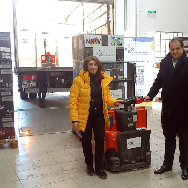 CDU-Landesminister Nathanael Liminski und Generalkonsulin Iryna Shum stehen im Lager des Blau-Gelben Kreuzes.