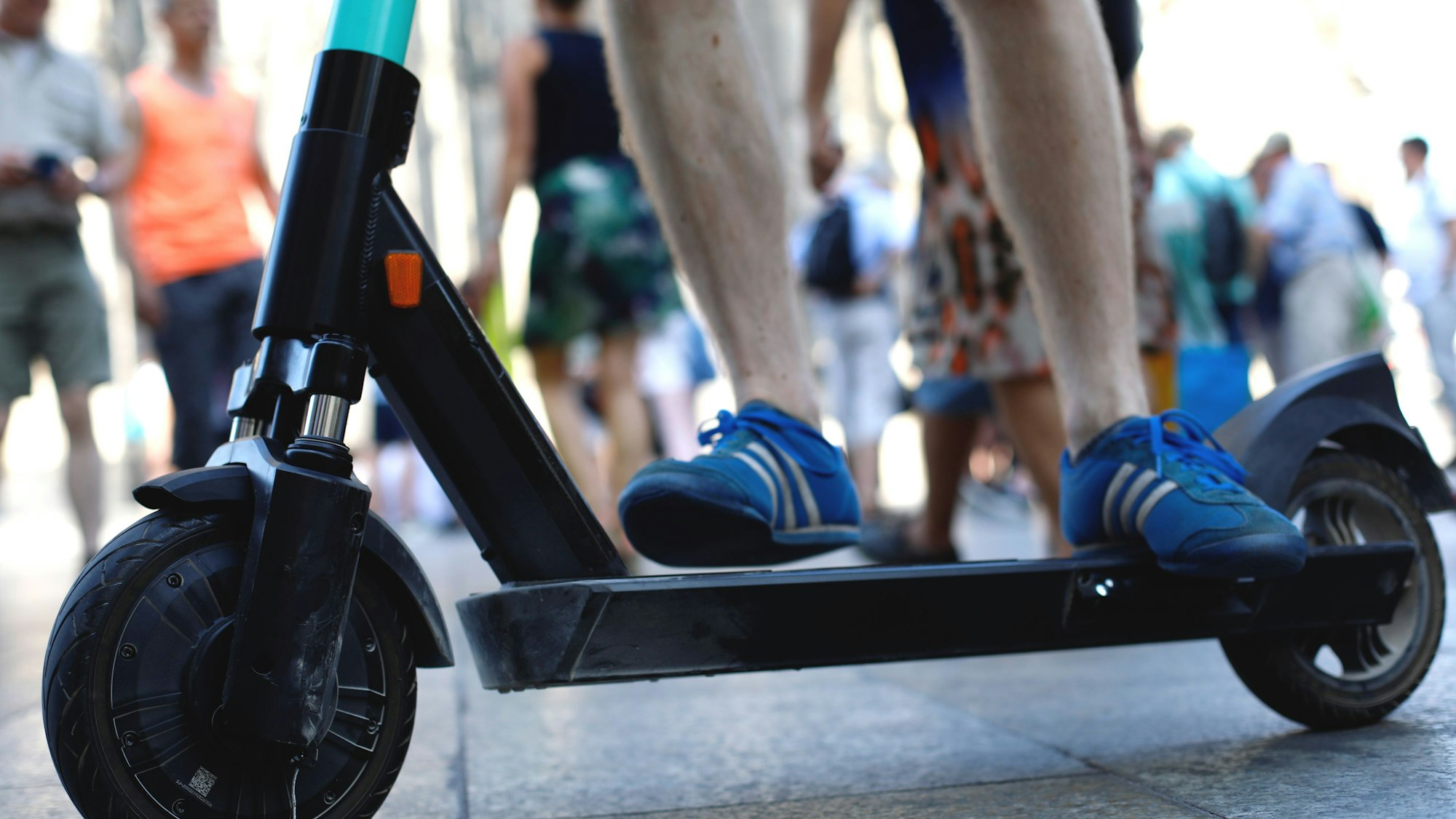 Ein E-Scooter ist zwischen Fußgängern unterwegs.