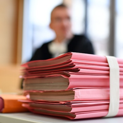 Ein Staatsanwalt sitzt im Landgericht hinter einem Stapel Akten.