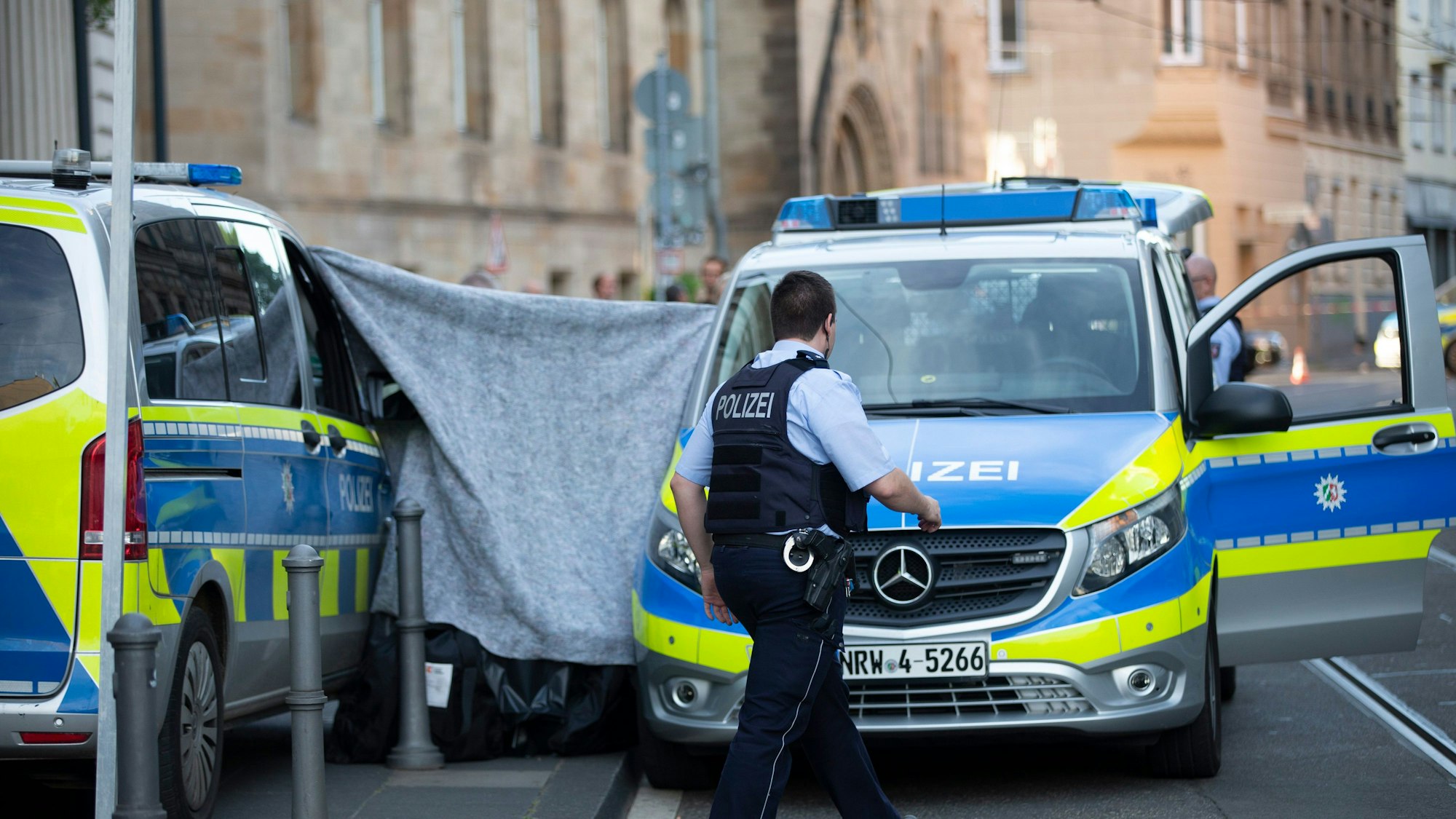 Ein Polizist vor einem Sichtschutz.