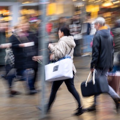 Menschen laufen mit Tüten bepackt durch eine Einkaufsstraße.