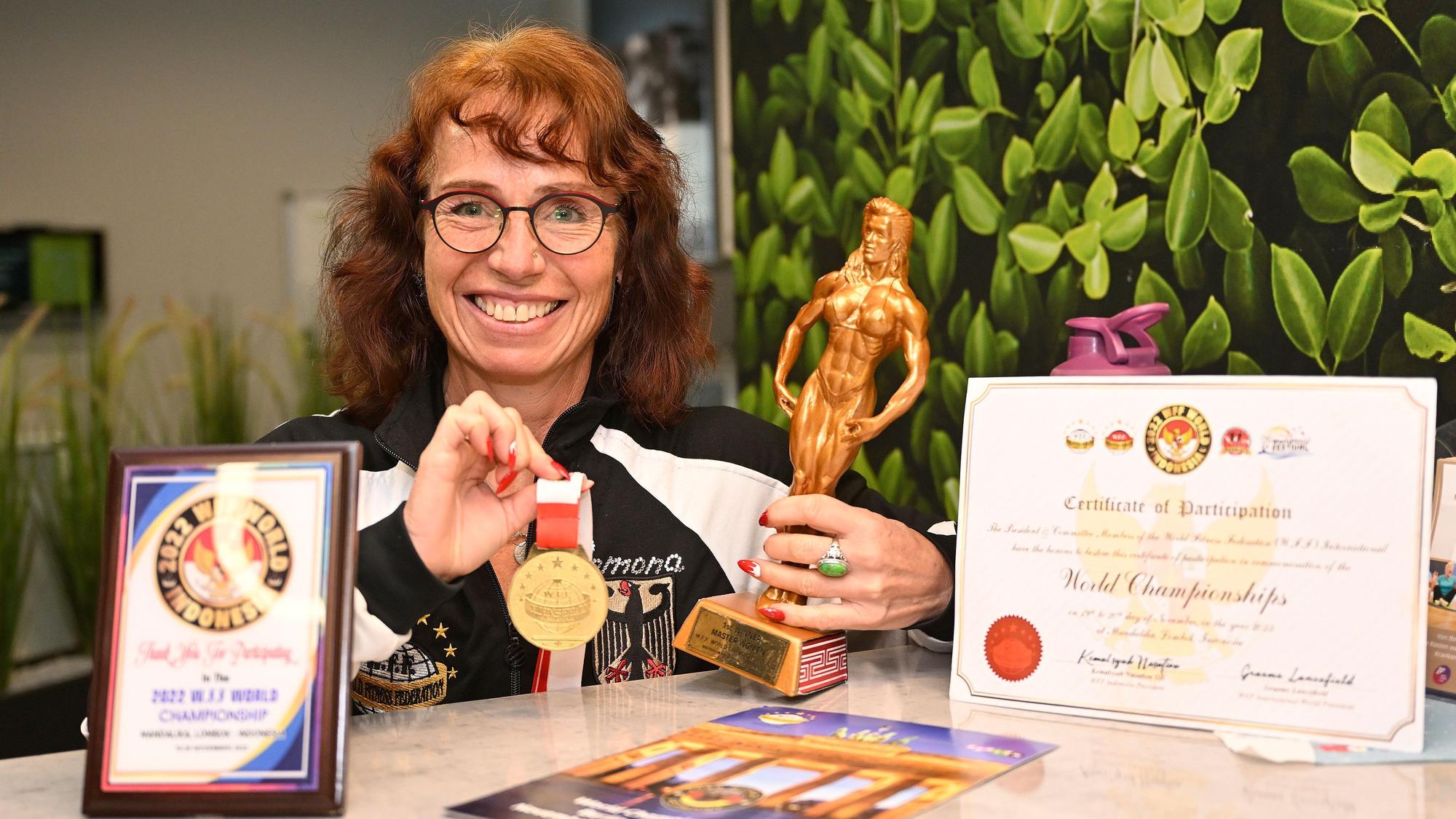 Bodybuilderin Ramona Przyborowski posiert mit ihrer Medaille und Siegerpokal.