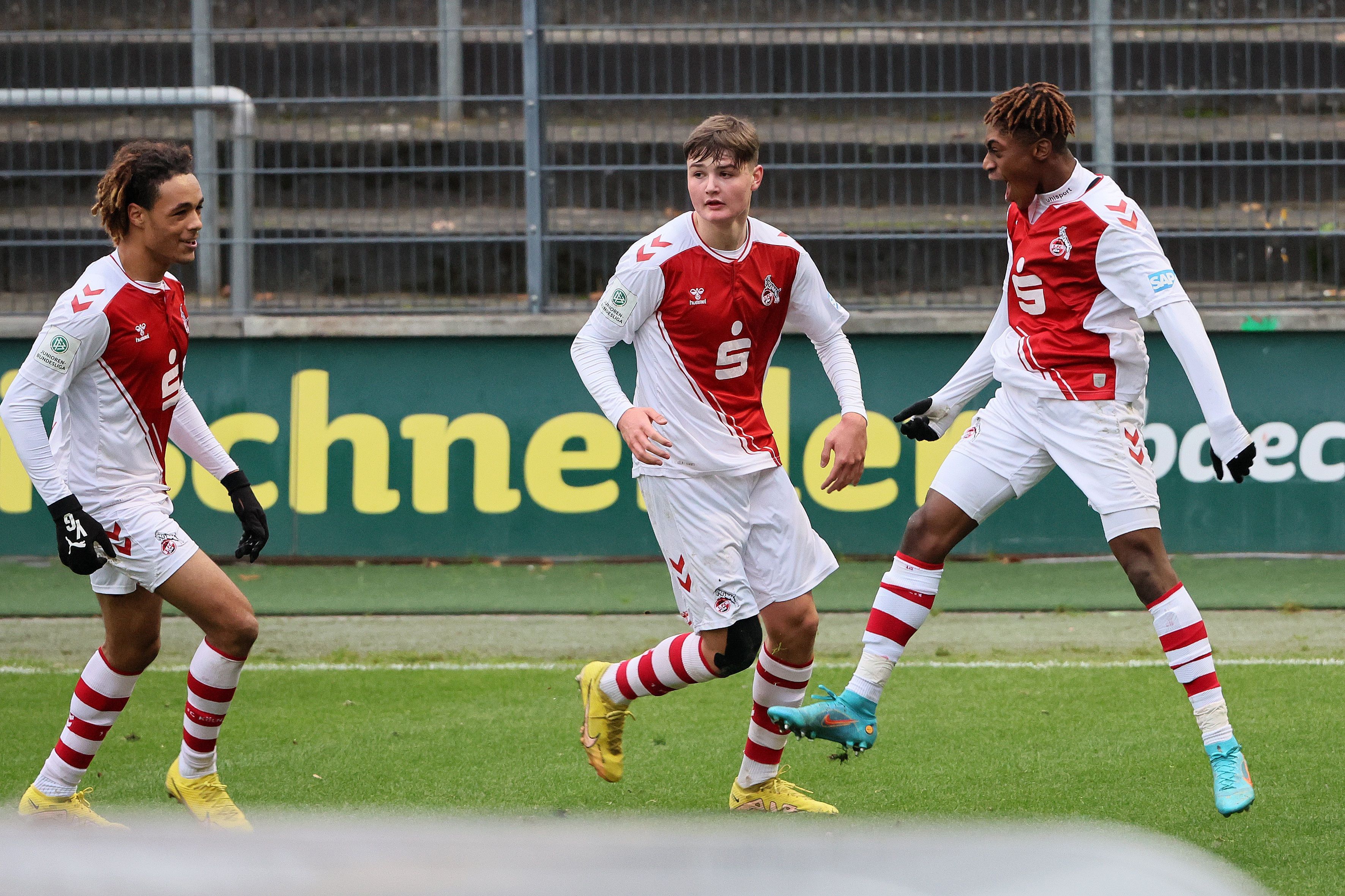 Drei Fußballspieler freuen sich über ein Tor.
