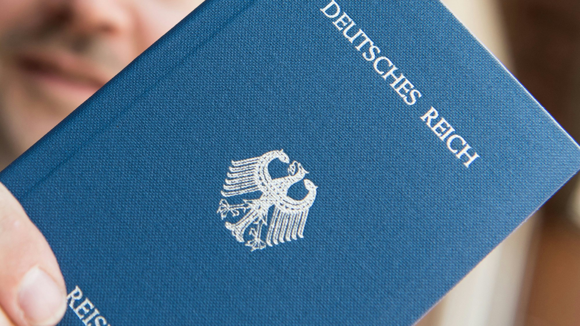 Zu sehen ist ein kleines blaues Buch mit der Aufschrift „Deutsches Reich“. Darunter befindet sich der Reichsadler, das Buch wird von einer Person in der Hand gehalten.