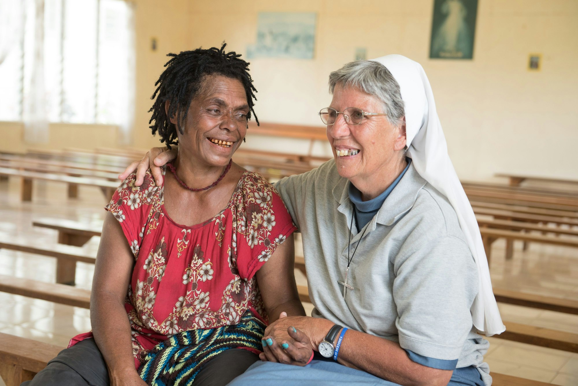 Die Ordensschwester Lorena Jenal sitzt mit der Überlebenden einer Hexenverbrennung in Papua Neuguinea in einer Kirche in Kundiawa und hält ihre Hand.