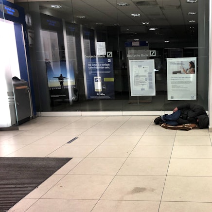 Ein Obdachloser schläft im Vorraum einer Filiale der Deutschen Bank in Köln (Symbolbild)