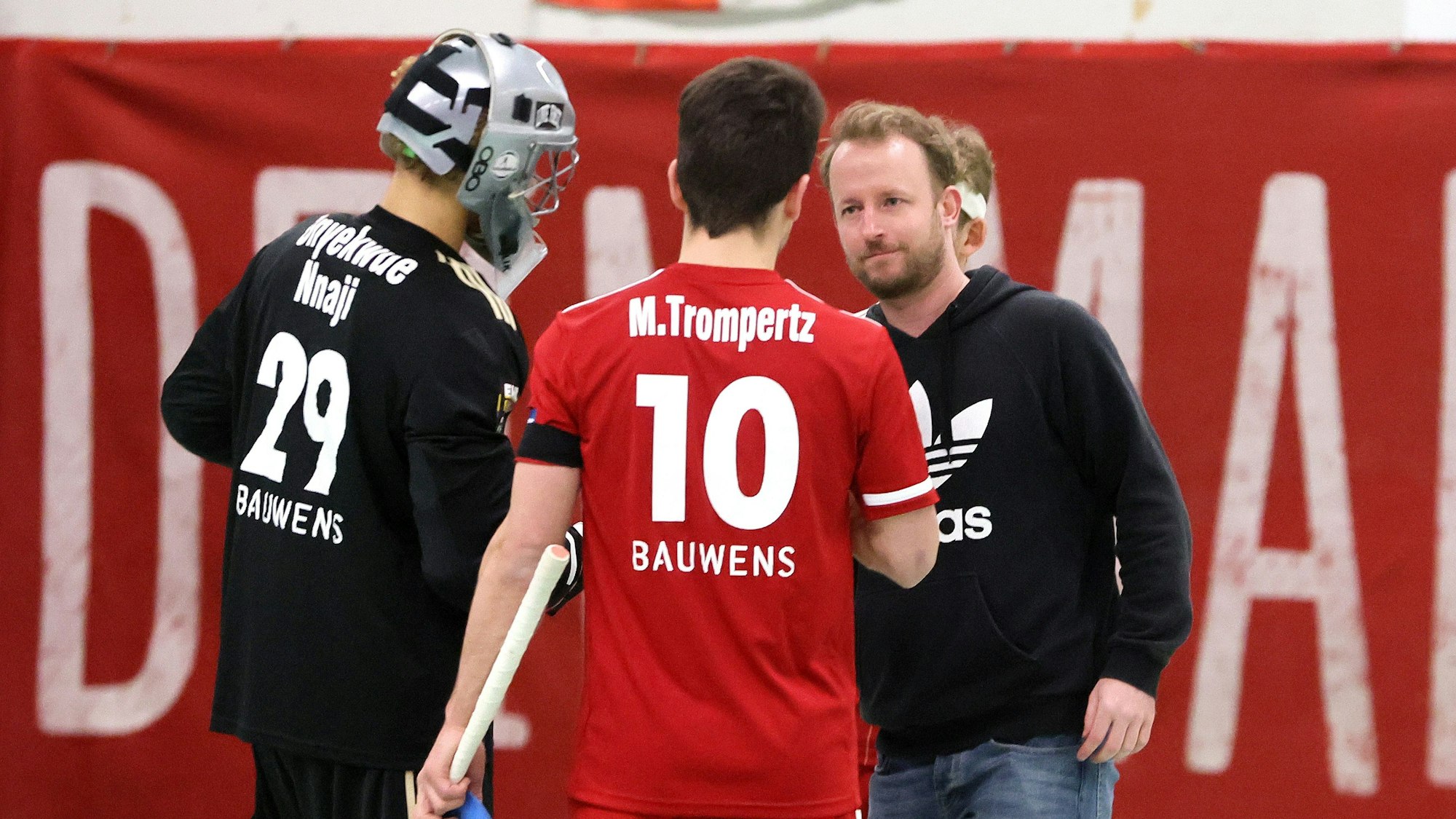 Ein Hockeytrainer gibt einem Spieler nach einer Partie die Hand und unterhält sich mit ihm.