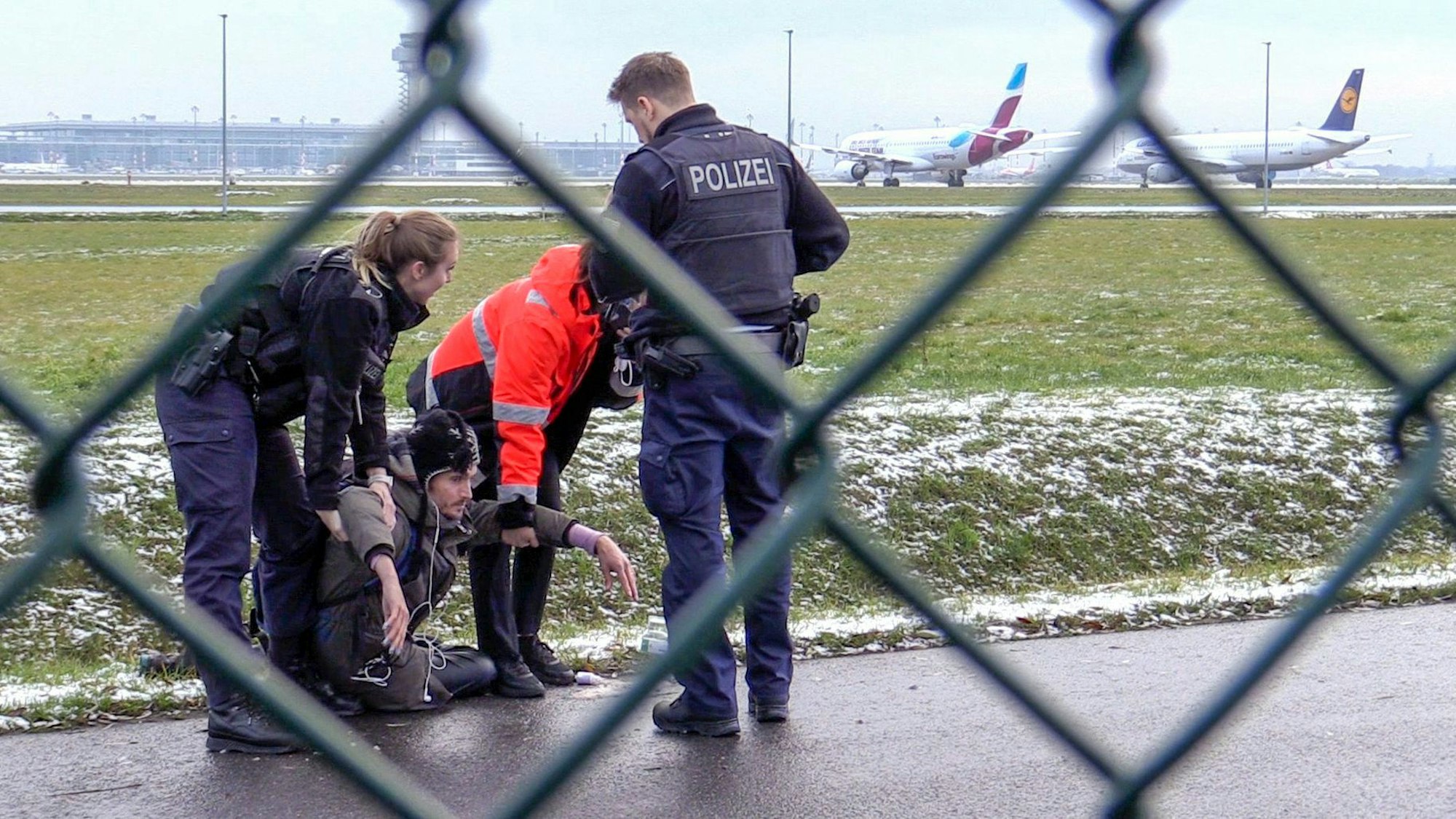 Zwei Beamte der Bundespolizei und ein Sicherheitsmitarbeiter steht mit einem sichergestellten Bolzenschneider an einem Zaun am BER-Flughafen.