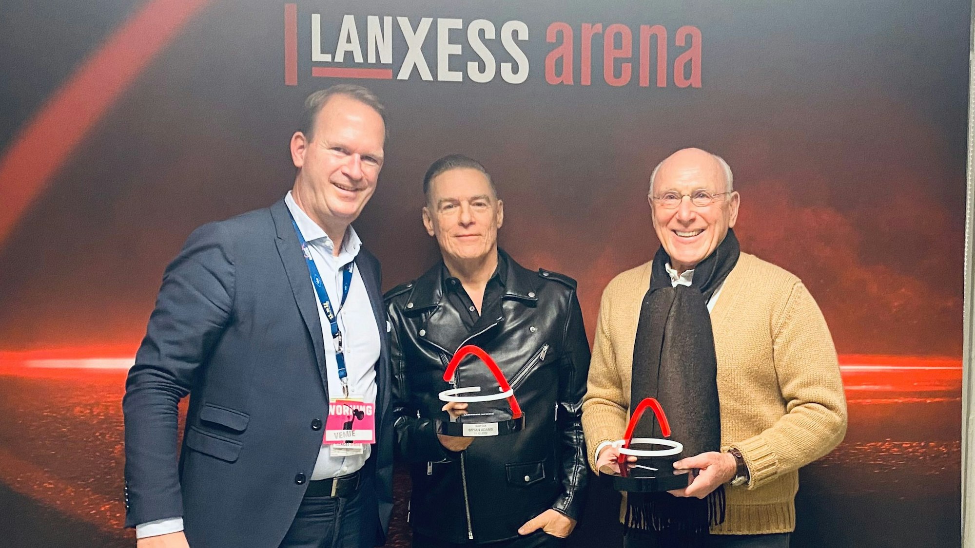 Stefan Löcher, Bryan Adams und Marek Lieberberg stehen nebeneinander und lächeln in die Kamera.