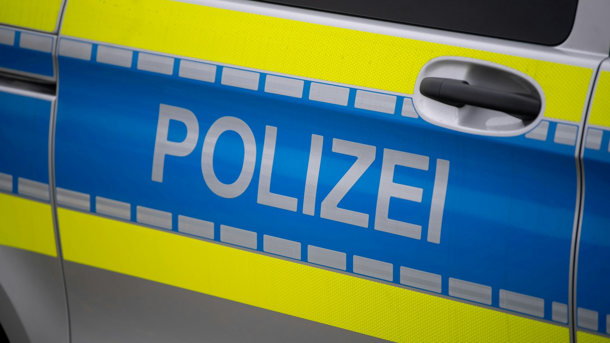 Das Symbolbild zeigt die Tür eines Einsatzfahrzeugs mit der Aufschrift Polizei.