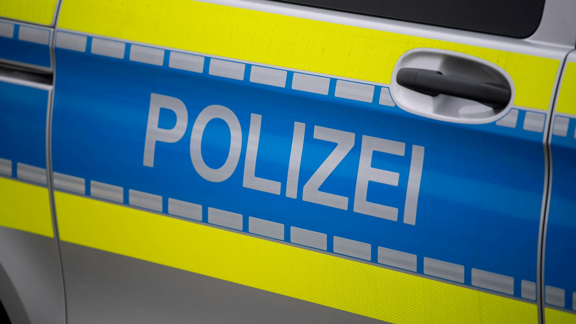 Das Bild zeigt die Tür eines Polizeiwagens mit der Aufschrift „Polizei“.