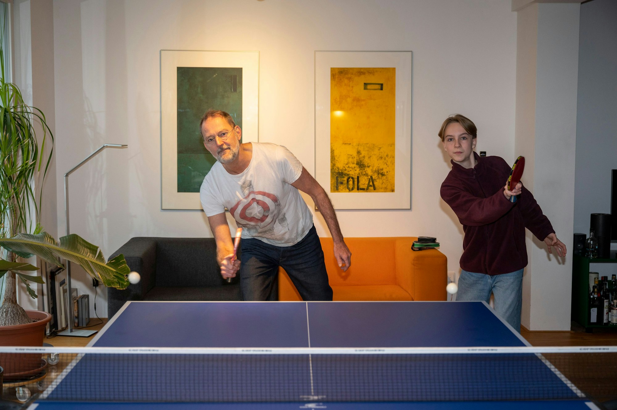 Olekseij und Michael Znamenacek stehen auf einer Seite einer Tischtennisplatte, beide schlagen Bälle auf die andere Seite.