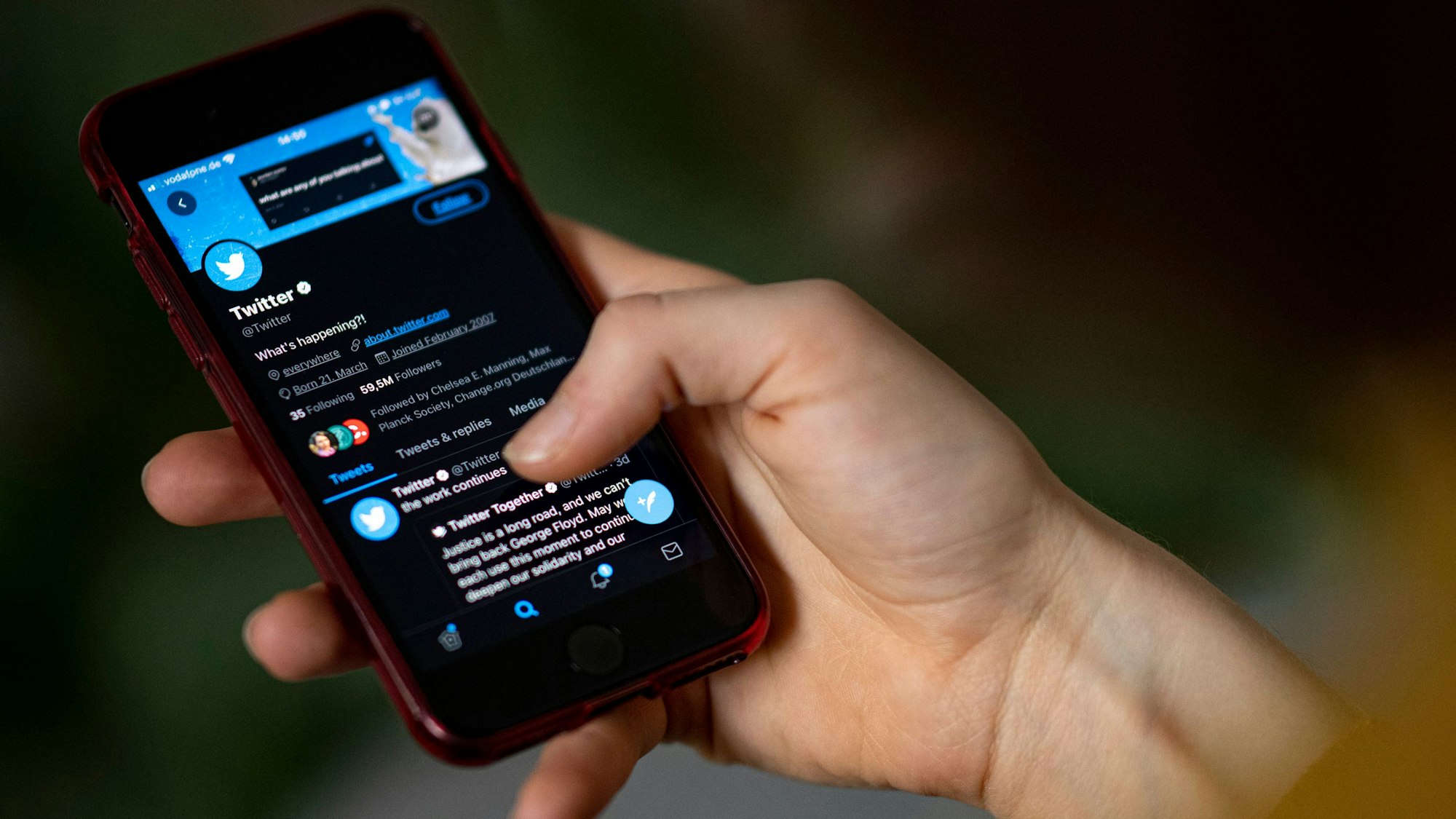 Eine Person hält ein Smartphone auf dem die Twitter-App zu sehen ist.