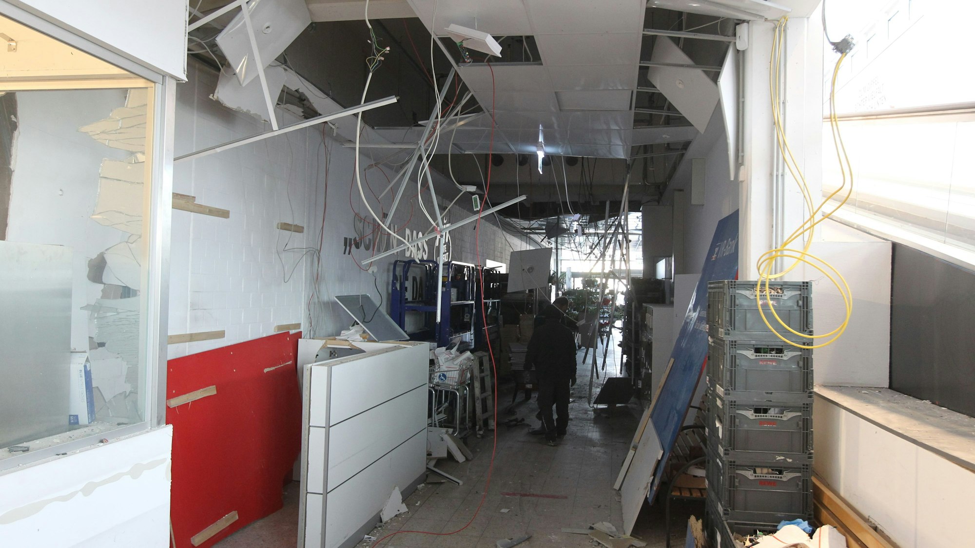 Nach Sprengung eines Geldautomaten in einem Supermarkt zeigt sich ein Bild der Zerstörung mit herunterhängenden Kabeln und Deckenplatten.