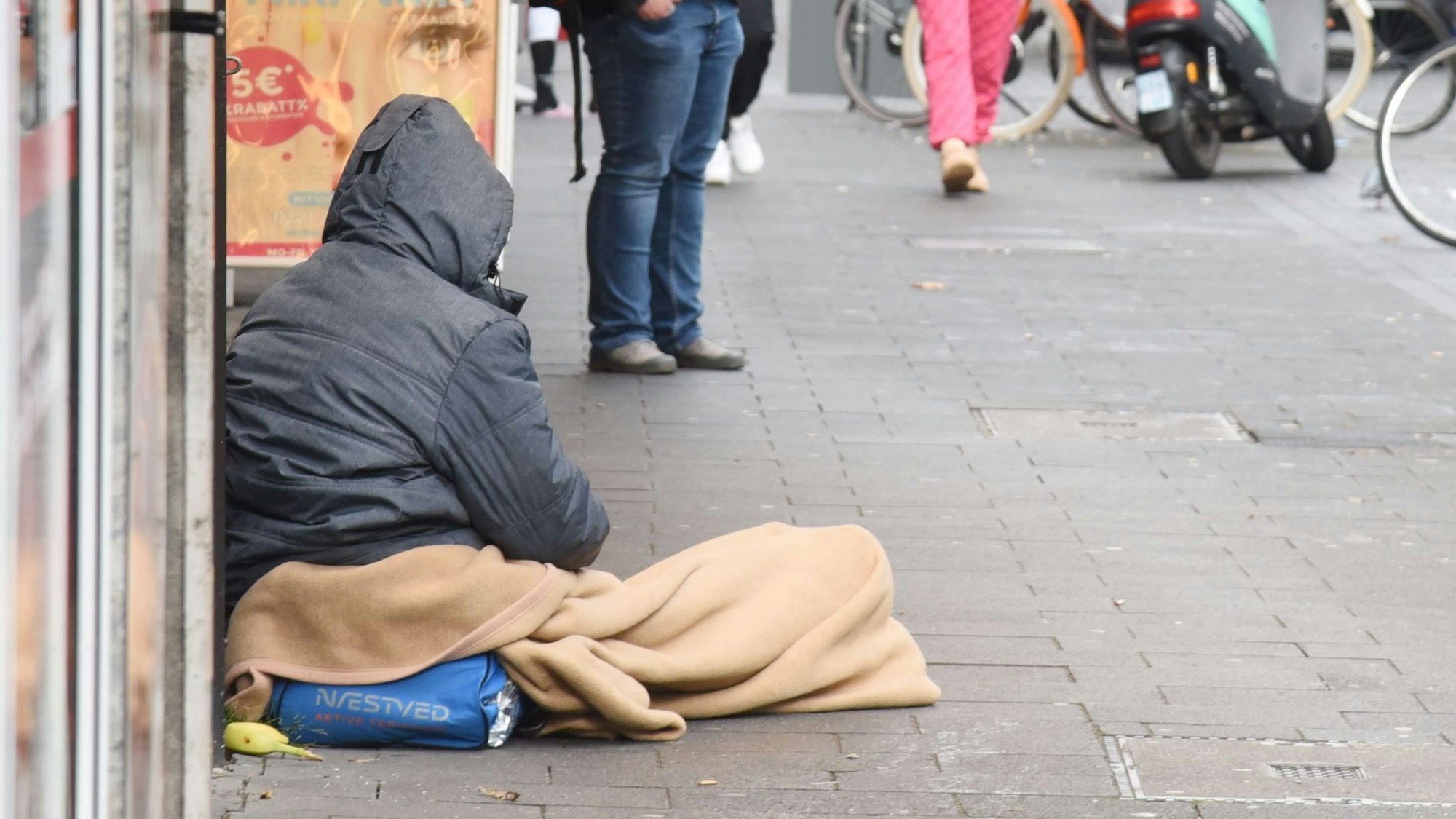 Ein Wohnungsloser sitzt auf einer Straße.