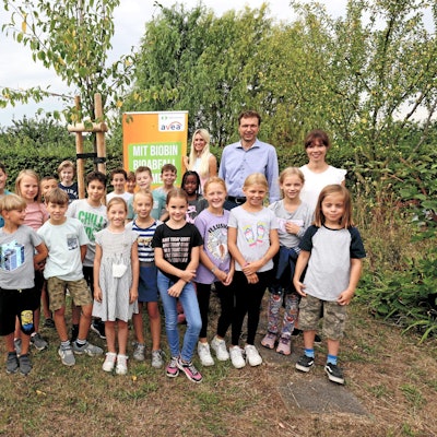 Kinder haben sich im Hitdorfer Kleingarten vor Plakaten mit dem Biotonnen-Maskottchen Biobin aufgestellt.