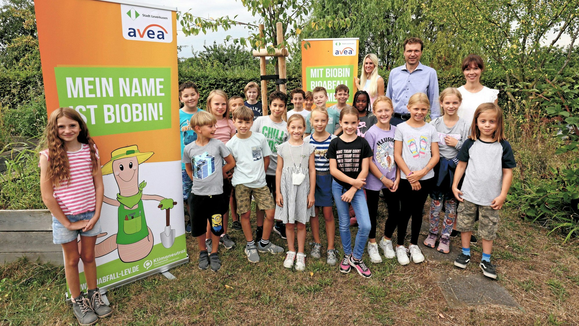Kinder haben sich im Hitdorfer Kleingarten vor Plakaten mit dem Biotonnen-Maskottchen Biobin aufgestellt.