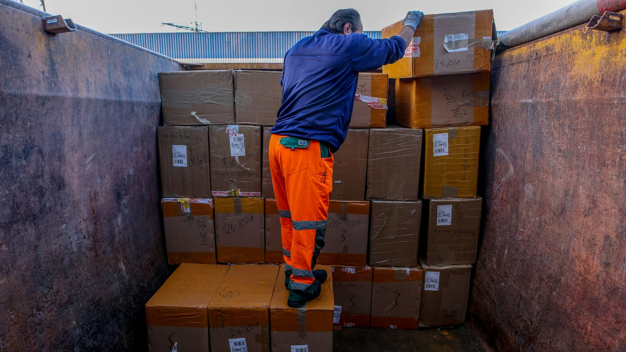 Ein Arbeiter stapelt die Kartons mit den Zigaretten auf dem Anhänger eines Lastwagens vor einer Lagerhalle in Köln.