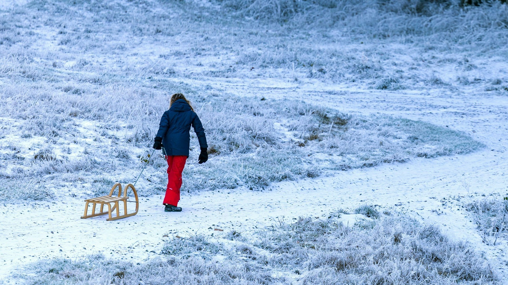 Eine junge Frau zieht einen Schlitten einen Berg hinauf.