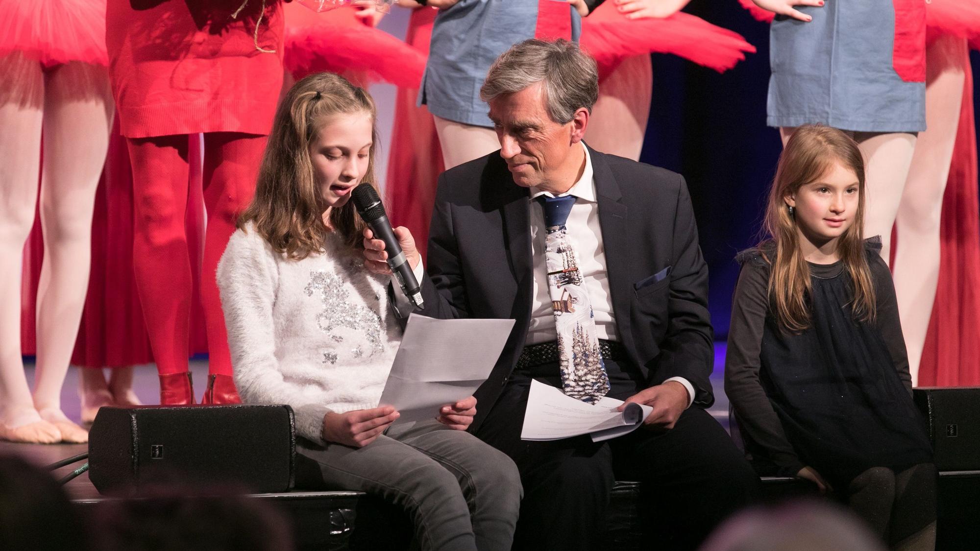 Jens Klein hält das Mikrofon für ein Mädchen, das einen Text liest.