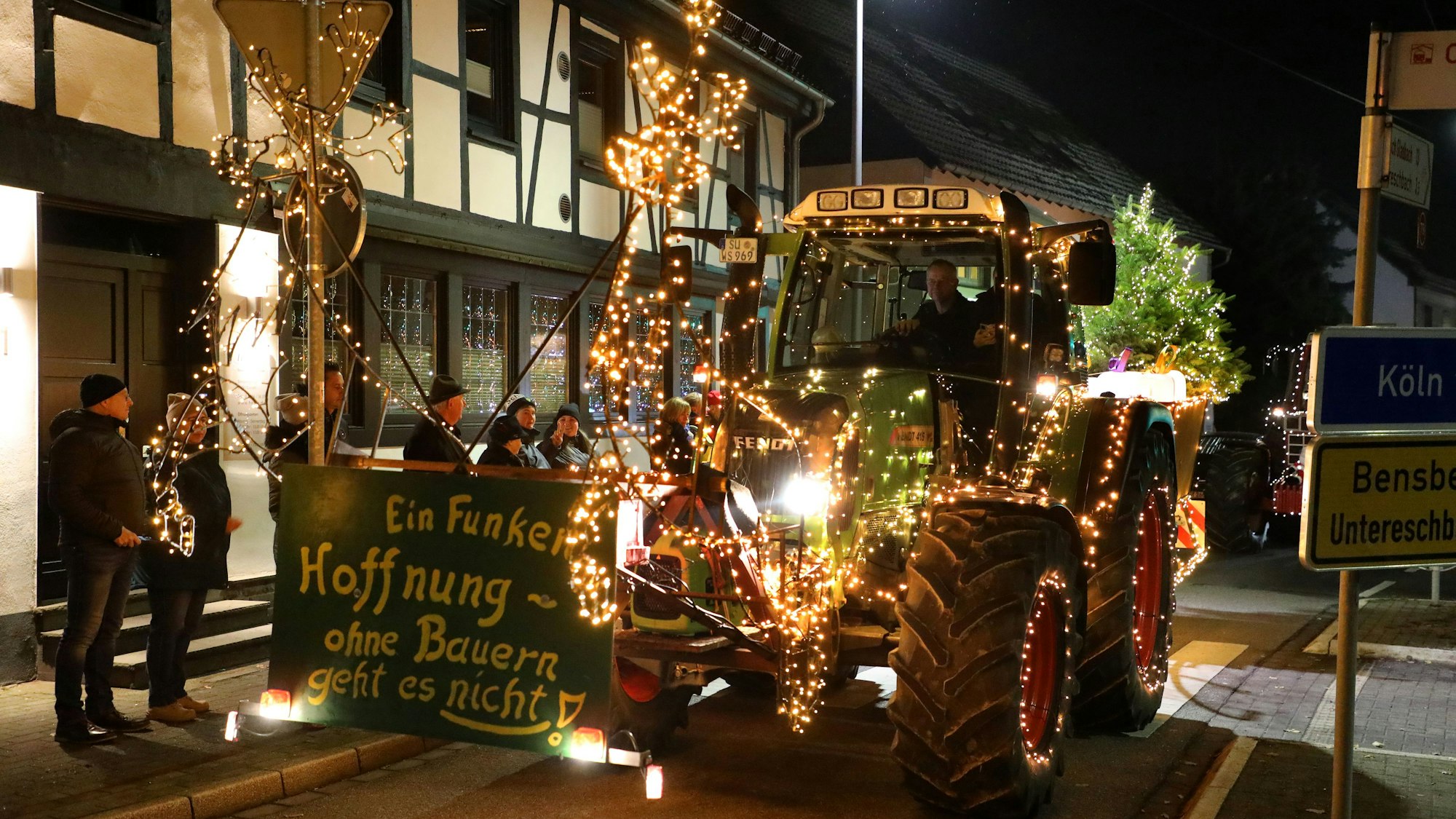 Ein grüner, ganz besonders mit Lichtern geschmückter Traktor fährt ein Schild mit der Aufschrift „Ein Funken Hoffnung – Ohne Bauern geht es nicht“ durch Overath.