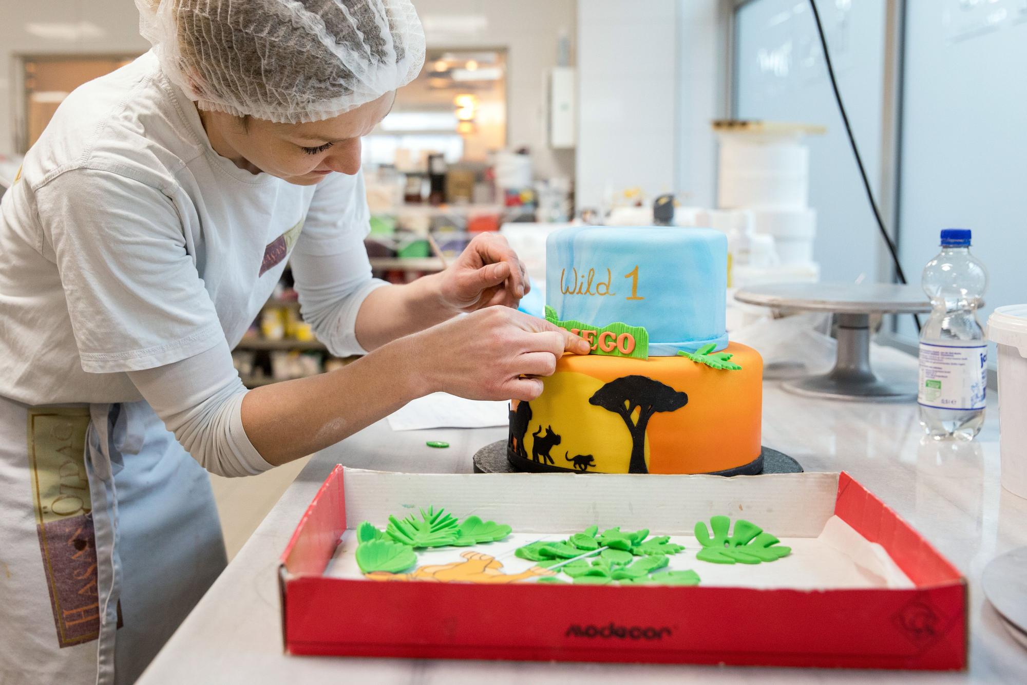 Eine Mitarbeiterin fertigt eine Torte mit einem Motiv aus „König der Löwen“ an.