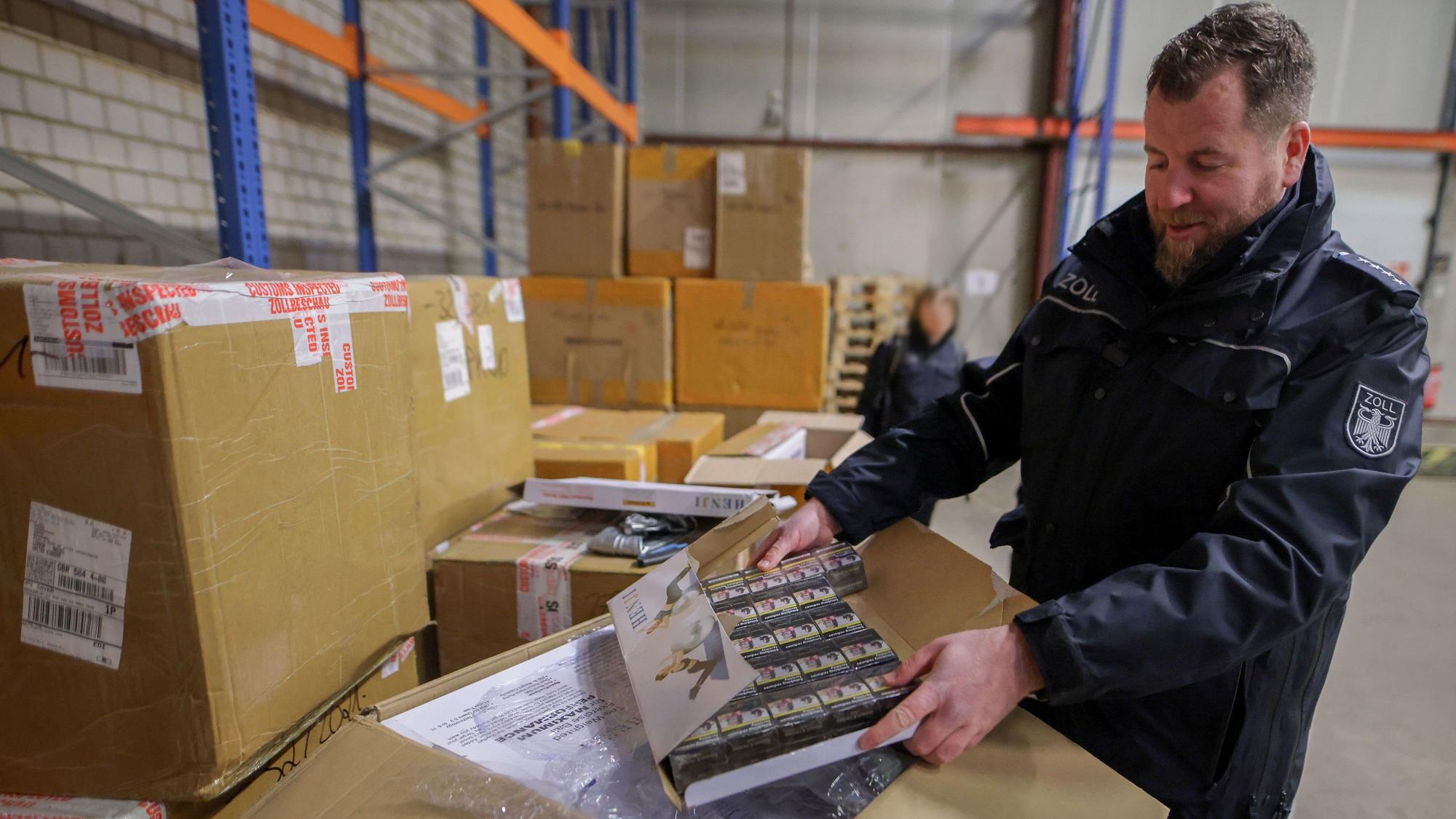 Zollsprecher Jens Ahland öffnet einen Karton, indem Zigarettenpackungen versteckt sind.