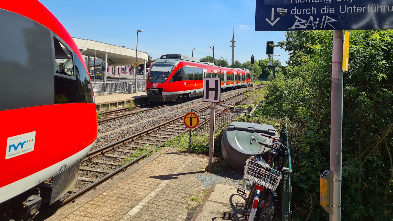 Am Bahnhof Bergheim begegnen sich zwei rote Regionalbahnen.