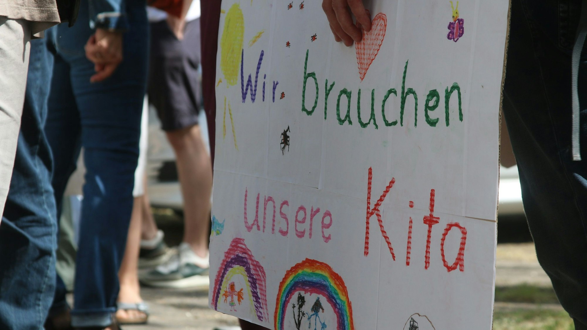 Eltern und Kinder der Evangelischen Kita in Zollstock demonstrieren mit Schildern gegen die geplante Schließung der Einrichtung.