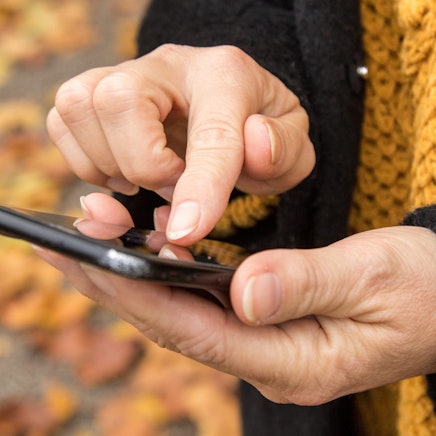 Eine Person hält ein Smartphone in der Hand und tippt darauf.