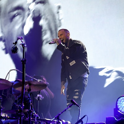 Kontra K singt in sein Mikrofon, neben ihm sieht man eine Wolfsstatue.