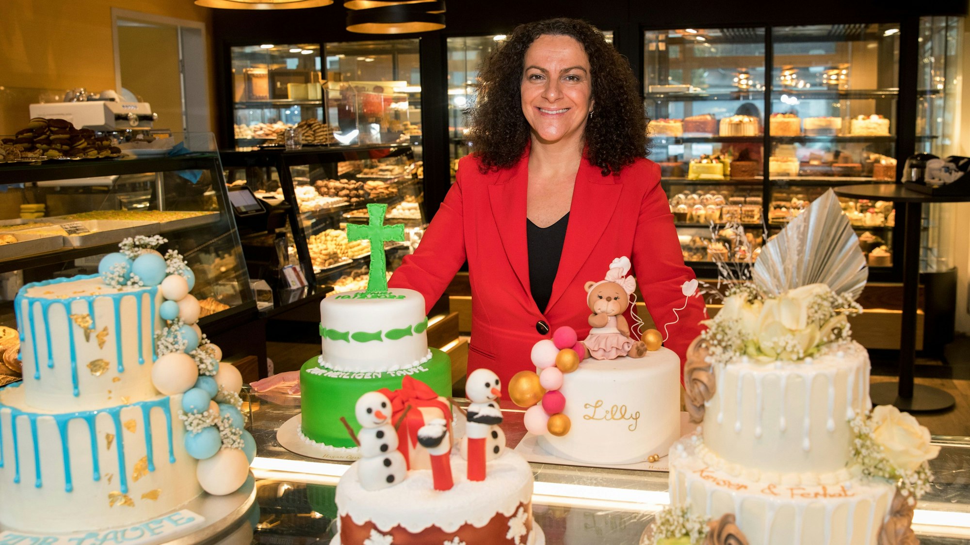 Chefin Hülya Özdag steht in der Konditorei in Stammheim, vor ihr dekorierte Torten mit Blumen, Schneemännern, einem Kreuz und einem Teddybären.