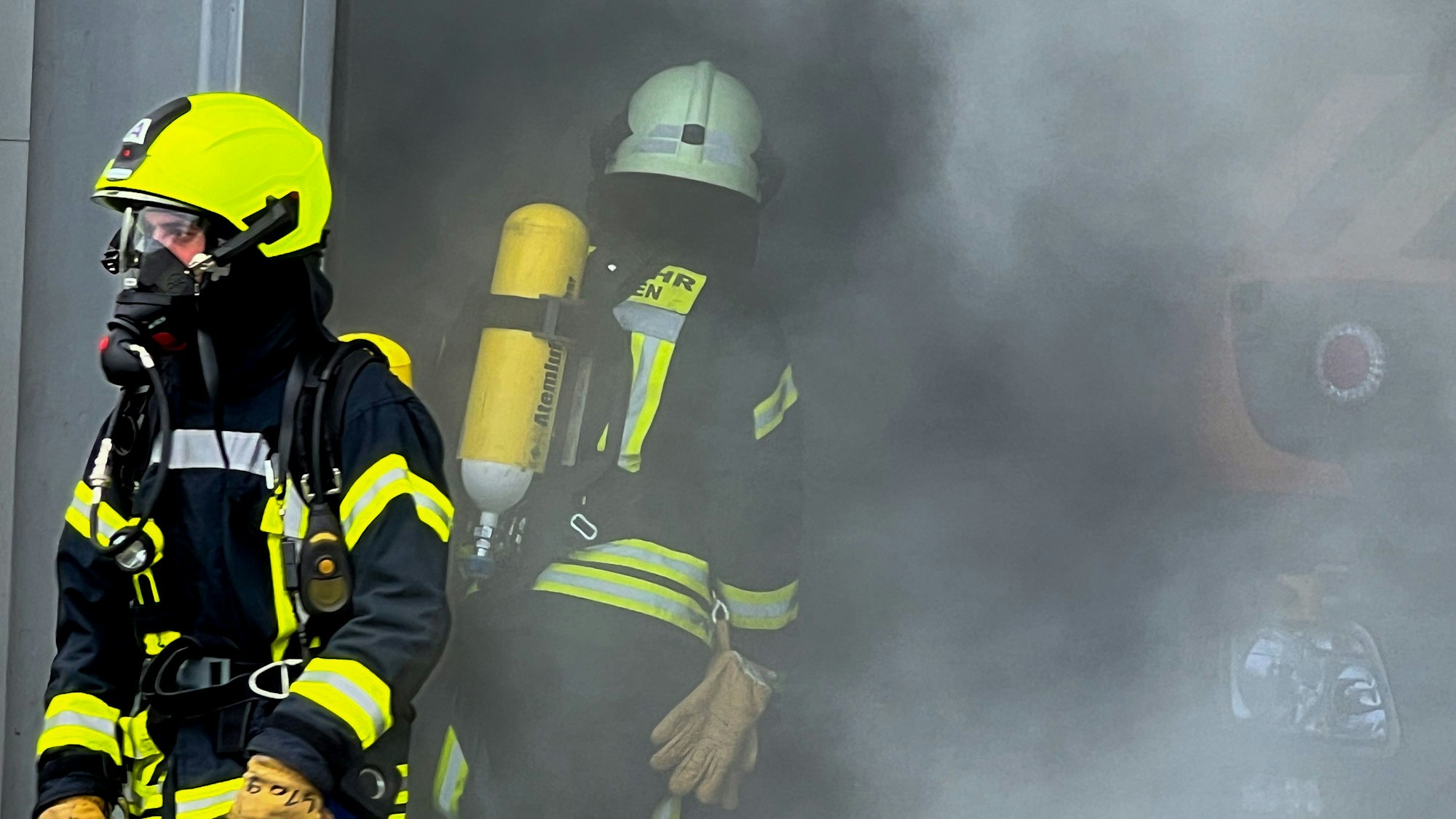 Dichter Nebel, zwei Feuerwehrleute mit Atemschutzmontur sind zu sehen.