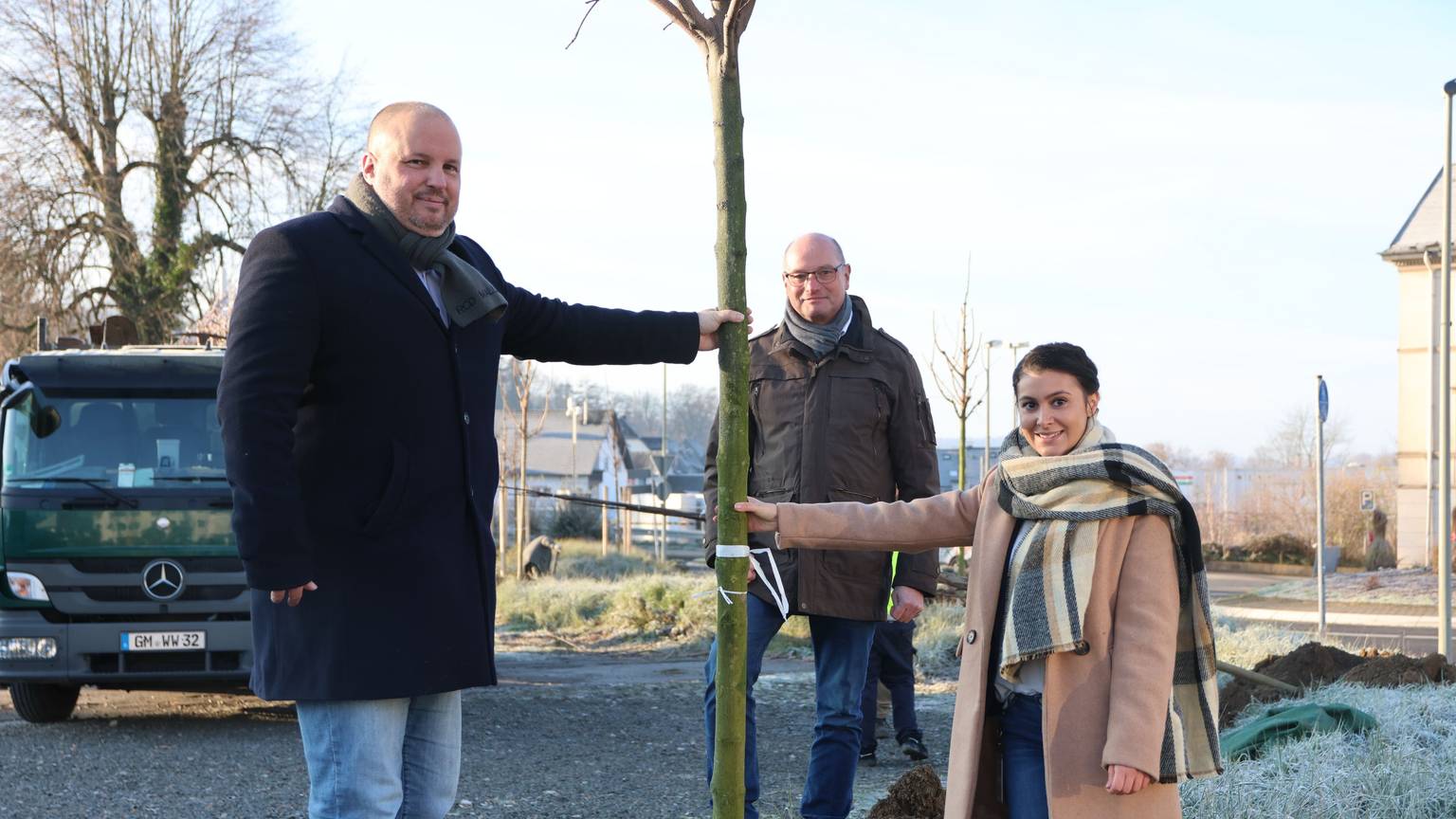 Zwei Männer und eine Frau pflanzen einen Baum in Bergneustadt.