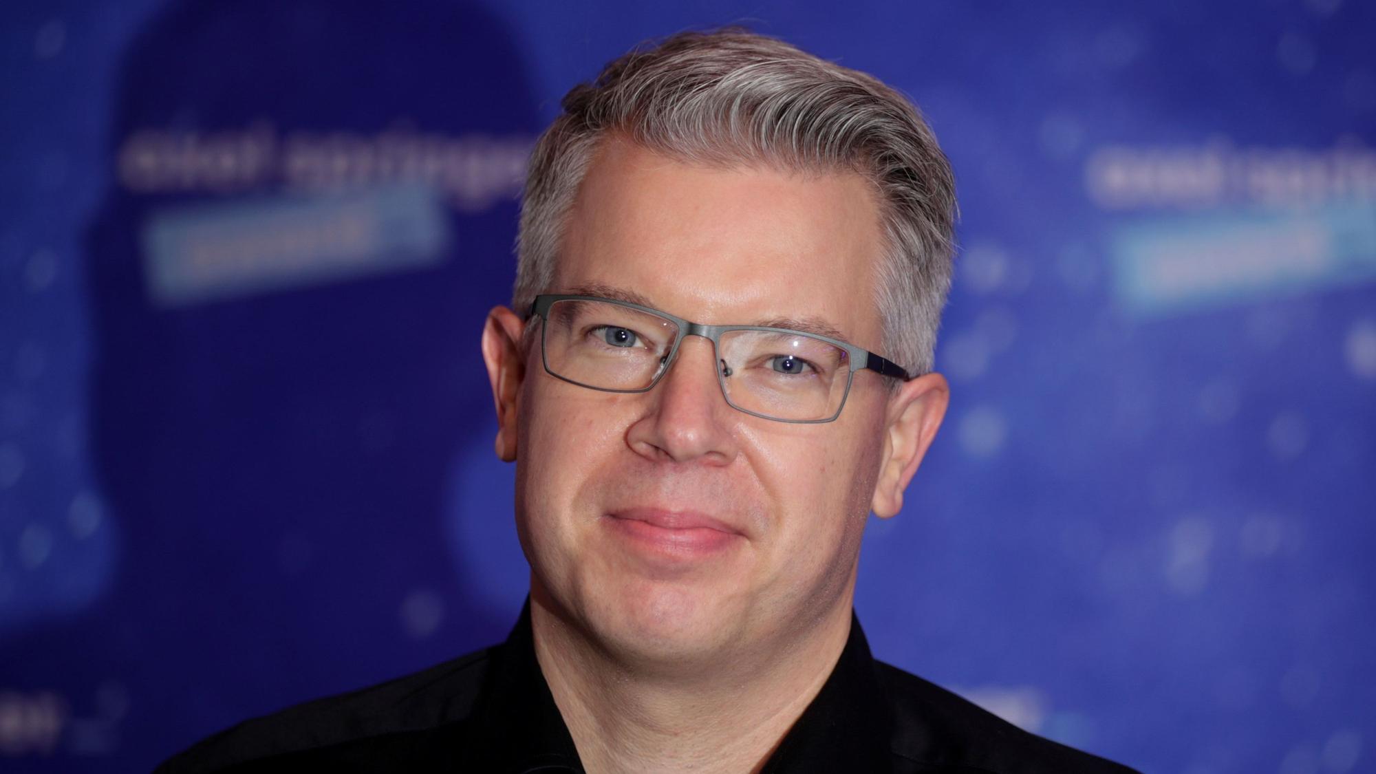 Frank Thelen, Unternehmer und bekannt aus „Die Höhle der Löwen“, blickt vor einem blauen Hintergrund in die Kamera.