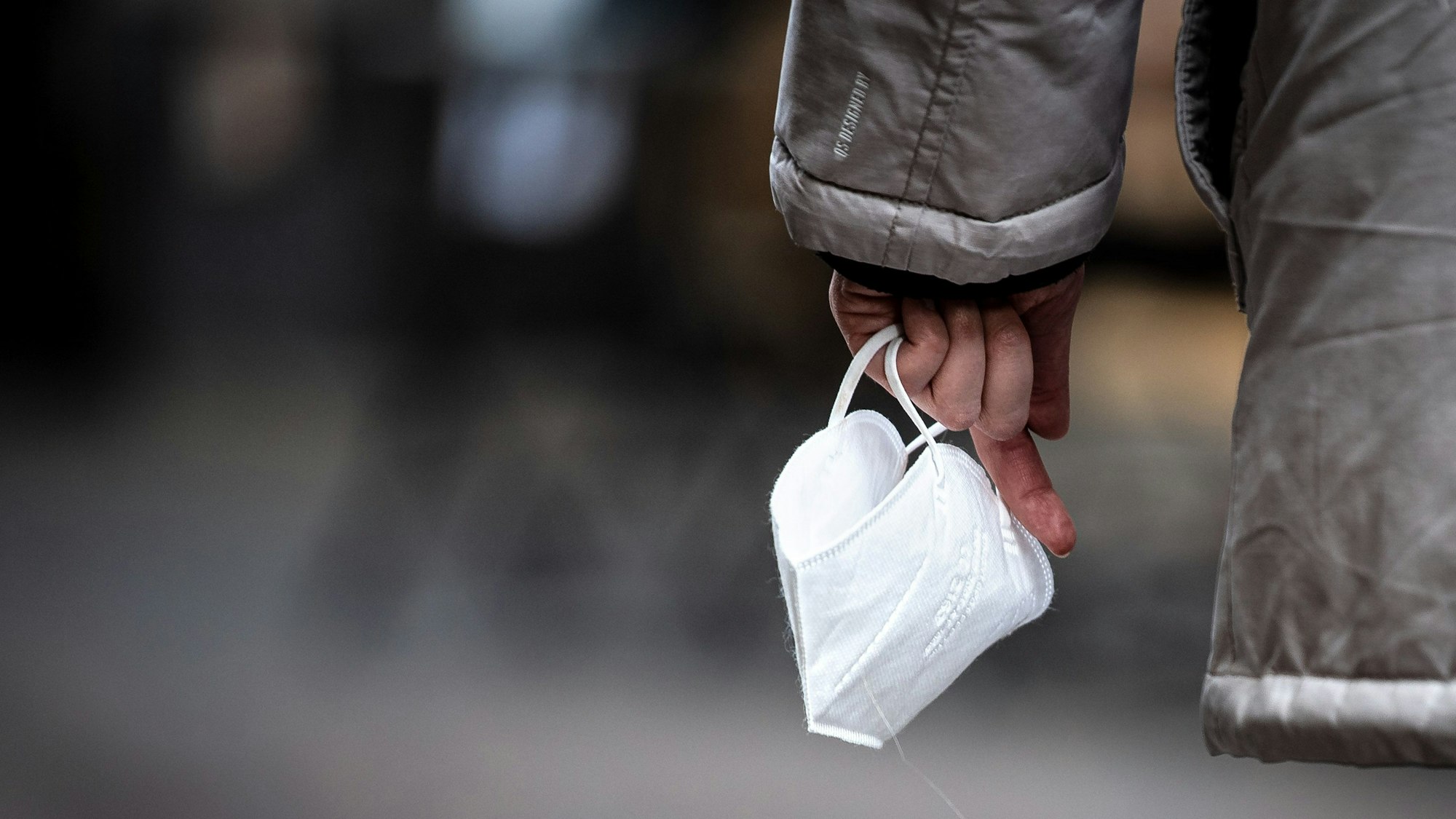 Eine Passantin hält eine FFP-2 Maske in der Hand.