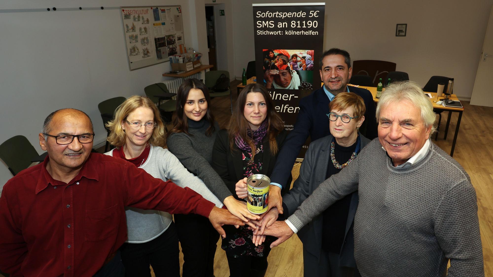 Ali Gececi, Dorothee Zimmer-Gececi, Anna Gececi, Berit Kranz, Vedat Akfer, Anke Brunn und Jürgen Roters der Initiative „Kölner helfen" halten gemeinsam eine Spenden-Spardose.
