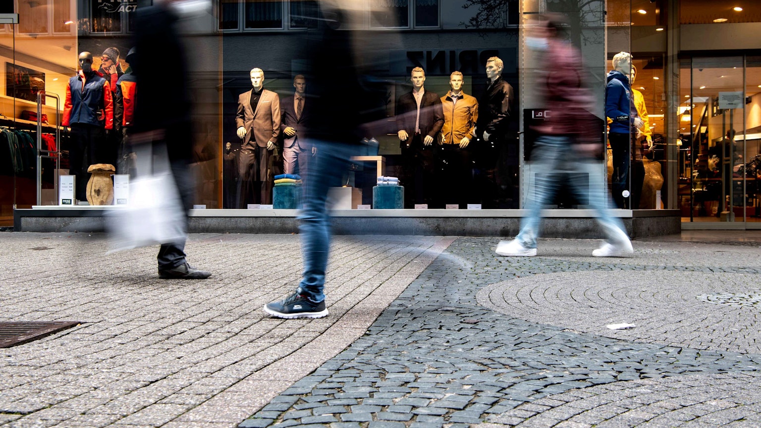 Menschen laufen an einem Bekleidungsladen in der Euskirchener Innenstadt vorbei.