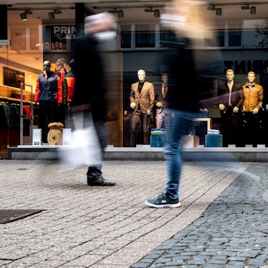Menschen laufen an einem Bekleidungsladen in der Euskirchener Innenstadt vorbei.
